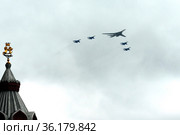 Группа истребителей СУ-35С и сверхзвуковой стратегический бомбардировщик дальней авиации Ту-160 во время парада пролетают над Красной площадью Москвы (2021 год). Редакционное фото, фотограф Free Wind / Фотобанк Лори