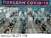 Люди заполняют документы в пункте вакцинации от новой коронавирусной инфекции COVID-19 в Гостином дворе в центре города Москвы, Россия (2021 год). Редакционное фото, фотограф Николай Винокуров / Фотобанк Лори