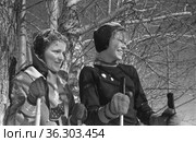 Фотопортрет юных лыжниц во время тренировки, девочки стоят под деревьями с лыжными палками и улыбаются, спортсменки в солнечную погоду, Алданский район, Якутия, 1961 год. Редакционное фото, фотограф Варфоломей Тетерин / Фотобанк Лори
