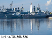 Старинный маяк среди военных кораблей Балтийского флота солнечным утром. Кронштадт. Россия (2021 год). Редакционное фото, фотограф Виктор Карасев / Фотобанк Лори
