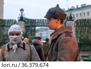 Реконструкторы - раненный солдат и боец Красной Армии. Акция памяти «900 дней и ночей» посвященная 77-летней годовщине снятия блокады Ленинграда во дворах Капеллы. Санкт-Петербург (2021 год). Редакционное фото, фотограф Румянцева Наталия / Фотобанк Лори
