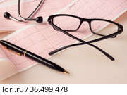 На столе электрокардиограмма с показаниями сердечного ритма, очки и стетоскоп. Стоковое фото, фотограф Sergei Gorin / Фотобанк Лори