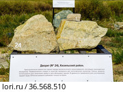 Arkaim, Chelyabinsk region, Russia - August, 24, 2021: Collection of rocks. The inscription on the plate: Diorite (No. 24), Kizil district. Crystalline-granular rock of magmatic origin, consisting of dark-colored minerals. Originally it served as a material for making sculptures. Now diorites are used to obtain crushed stone and cladding of buildings. In ancient times, it was used for the manufacture of tools. In Russia, diorites are mined only in the Urals. Редакционное фото, фотограф Вадим Орлов / Фотобанк Лори