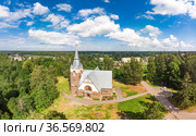 Aerial panoramic view to old lutheran church kirk Ryaysyalya designed by architect Joseph Stenback in style of Finnish romanticism, Art Nouveau in sunny summer day. Melnikovo, Leningrad region, Russia. Стоковое фото, фотограф Алексей Ширманов / Фотобанк Лори