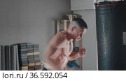 Shirtless sweaty young man boxer punching the punching bag. Стоковое видео, видеограф Константин Шишкин / Фотобанк Лори