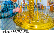 an elderly woman to put a candle in a candlestick in a church for a commemoration (2021 год). Редакционное фото, фотограф Акиньшин Владимир / Фотобанк Лори