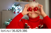 Child in a Santa hat holds red balloons, boy is playing with Christmas tree toys. Waiting for new year. Positive pre-holiday mood. Decoration of Christmas tree with red balls. Dabble with balls. Стоковое видео, видеограф Ирина Ткачук / Фотобанк Лори