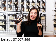 Positive woman with two revolvers in hands in gun shop. Стоковое фото, фотограф Яков Филимонов / Фотобанк Лори