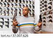 Latino choosing sporting and hunting revolvers in gunsmith shop. Стоковое фото, фотограф Яков Филимонов / Фотобанк Лори
