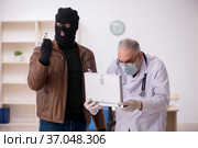 Masked man burglar bribing old doctor for getting vaccine. Стоковое фото, фотограф Elnur / Фотобанк Лори