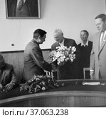 Космонавт Валерий Быковский жмёт руку и принимает цветы от пожилого мужчины, лётчик на встрече с партийными работниками и большевиками, Якутия, 1965. Редакционное фото, фотограф Варфоломей Тетерин / Фотобанк Лори