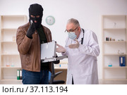 Masked man burglar bribing old doctor for getting vaccine. Стоковое фото, фотограф Elnur / Фотобанк Лори