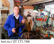 Gunsmith with Kalashnikov assault rifle in weapons workshop. Стоковое фото, фотограф Яков Филимонов / Фотобанк Лори