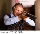 Concentrated man practicing shotgun shooting at firing range. Стоковое фото, фотограф Яков Филимонов / Фотобанк Лори
