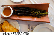 Calcots onions served on plate with Romesco sauce - traditional Catalan dish. Стоковое фото, фотограф Яков Филимонов / Фотобанк Лори
