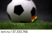 Ghana flag on the football field. Soccer championship. Football classic black and white ball rolls in the background. Sports Competition. The national flag of the country. Green fresh lawn grass. Стоковое видео, видеограф Ирина Ткачук / Фотобанк Лори