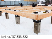 First stage of erection of wooden frame house, housebuilders working with timber in winter season. Стоковое фото, фотограф Кекяляйнен Андрей / Фотобанк Лори
