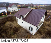 Steel roof of small white villa, house standing on lot of land without any fencing. Стоковое фото, фотограф Кекяляйнен Андрей / Фотобанк Лори