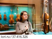 Interested brunette visiting exhibition of medieval musical instruments in museum. Стоковое фото, фотограф Яков Филимонов / Фотобанк Лори