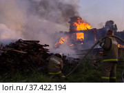 Сотрудники пожарной службы тушат огонь. Пожарные на месте пожара. Пожар в деревне. Горят деревянные дома в деревне Ранцево Тверской области. Fire service employees extinguish the fire. Firefighters at the scene of the fire. A fire in the village. Burning wooden houses in the village of Rantsevo, Tver region. (2021 год). Редакционное фото, фотограф Мария / Фотобанк Лори