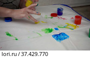 Finger safe childrens paints on the table and children's hands. An adult hand draws the sun. Стоковое видео, видеограф Наталья Гармашева / Фотобанк Лори