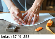 Рабочее место портного. Женщина прикалывает выкройку к ткани. Working process of a dressmaker. Closeup photo of craftsperson's hands. Стоковое фото, фотограф Ekaterina M / Фотобанк Лори