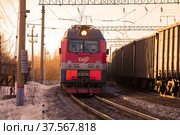 Российский электровоз 2ЭС5К «Ермак» и встречный грузовой поезд в повороте мартовским солнечным вечером. Северная железная дорога (2021 год). Редакционное фото, фотограф Виктор Карасев / Фотобанк Лори
