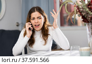 Wrathful woman quarreling on phone in apartment. Стоковое фото, фотограф Яков Филимонов / Фотобанк Лори