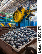 Stepnogorsk, Kazakhstan - April 04, 2012: Bearing production plant workshop. Mechanic press for steel balls stamping. Hot balls in metal hopper. Center in focus. Редакционное фото, фотограф Alexey Rezvykh / Фотобанк Лори