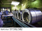 Stepnogorsk, Kazakhstan - April 04, 2012: Bearing production plant. Ready bearings on quality control line. Low depth of field, young worker is out of focus. Редакционное фото, фотограф Alexey Rezvykh / Фотобанк Лори