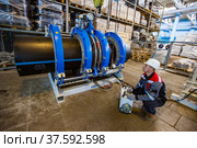 Stepnogorsk, Kazakhstan - April 04, 2012: Plastic pipes production plant. Engineer adjusting pipes joining equipment. Редакционное фото, фотограф Alexey Rezvykh / Фотобанк Лори