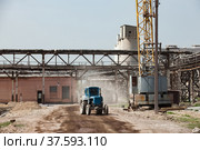 Grey pipelines and concrete construction and mobile crane on grey sky. Tractor Belarus on dusted soil. Old plant renovation. Стоковое фото, фотограф Alexey Rezvykh / Фотобанк Лори