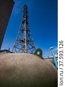 Phosphoric fertilizers factory. Plant chimney and the metal girder and round metal tank on blue sky background. Стоковое фото, фотограф Alexey Rezvykh / Фотобанк Лори