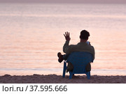 Silhouette of a guy sitting on the beach and chatting on the phone. Стоковое фото, фотограф Татьяна Дворецкая / Фотобанк Лори