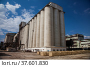 Kyzylorda Province, Kazakhstan - April 30, 2019. Outdated Soviet concrete grain elevator. Blue sky, clouds. Стоковое фото, фотограф Alexey Rezvykh / Фотобанк Лори