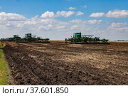 North Kazakhstan Province, Kazakhstan - May 12, 2012: Spring sowing campaign. John Deere tractors cultivating soil with harrow. Blue sky, clouds. Стоковое фото, фотограф Alexey Rezvykh / Фотобанк Лори