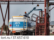 Tank truck filling station of oil refinery plant. Worker on top of tank. Blue sky. (2012 год). Редакционное фото, фотограф Alexey Rezvykh / Фотобанк Лори