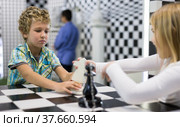Boy adn girl solving puzzle together in room stylized like chessboard. Стоковое фото, фотограф Яков Филимонов / Фотобанк Лори