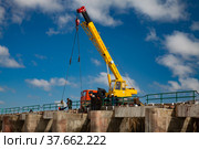 Kok-aral, Kazakhstan - May 03, 2012: Small Aral Sea Kok-aral dam. Mobile crane and workers lifting water shutters in flood. Blue sky, white clouds. Редакционное фото, фотограф Alexey Rezvykh / Фотобанк Лори