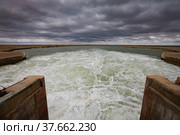 Small Aral Sea Kok-aral dam. Kazakhstan, Kyzylorda region. Concrete supports, metal shutters. turbulent water after dam.Grey storm sky. Стоковое фото, фотограф Alexey Rezvykh / Фотобанк Лори