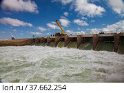 Small Aral Sea Kok-aral dam.Water discharge in flood. Open gates. Yellow mobile crane and workers on dam. Стоковое фото, фотограф Alexey Rezvykh / Фотобанк Лори