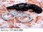 Наручники и пистолет, лежащие на деньгах, крупным планом. Фон из российских рублей. Стоковое фото, фотограф Владимир Ходатаев / Фотобанк Лори
