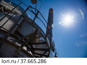 Sulphuric acid plant. Furnace for sulfur burning for dioxide and smoking stack (plant chimney). Close-up. Blue sky with sun background. Kzylorda region, Kazakhstan. Стоковое фото, фотограф Alexey Rezvykh / Фотобанк Лори