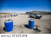 Khromtau, Aktobe region, Kazakhstan - May 06 2012: gold mine. Hand-made road balustrade of plastic barrel with concrete. Off-road car on background.. Редакционное фото, фотограф Alexey Rezvykh / Фотобанк Лори