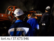 Khromtau, Aktobe region, Kazakhstan - May 06 2012: Gold mine underground gallery. Ore mining machine and engineers. Редакционное фото, фотограф Alexey Rezvykh / Фотобанк Лори