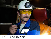 Khromtau, Aktobe region, Kazakhstan - May 06 2012: Gold ore mining. Mine truck driver. adult Asian man in white hardhat with headlight and yellow protective glasses. Редакционное фото, фотограф Alexey Rezvykh / Фотобанк Лори
