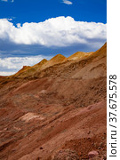 Bauxite open cast (open cut) mining. Color aluminium ore quarry. Big yellow piles of empty rocks. (Slag heaps). On blue sky with clouds. Vertical photo. Стоковое фото, фотограф Alexey Rezvykh / Фотобанк Лори