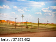 Aluminium ore quarry. Bauxite clay open-cut mining. Heaps of empty stones with green grass. Concrete poles on blue sky background. Стоковое фото, фотограф Alexey Rezvykh / Фотобанк Лори