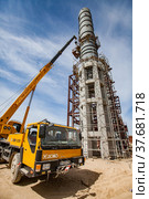 Aktau, Kazakhstan - May 19, 2012: Construction of asphaltic bitumen plant refinery column. Metal distillation tower and hydraulic hoist. Редакционное фото, фотограф Alexey Rezvykh / Фотобанк Лори