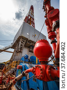 Uralsk region, Kazakhstan - May 24 2012: Oil deposit Zhaikmunai. Mud pump for drilling rig, pipes and equipment. Oil rig on blue sky with clouds background. Стоковое фото, фотограф Alexey Rezvykh / Фотобанк Лори